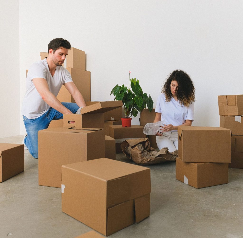 A couple experiencing the exhausting and overwhelming reality of packing and moving boxes during a property sale.